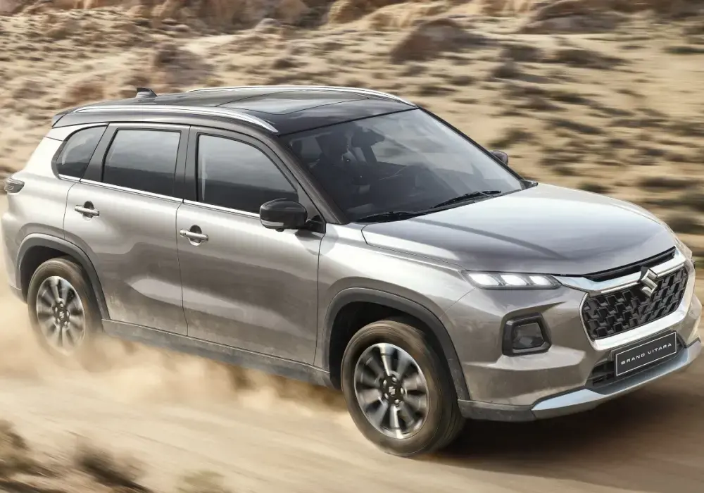 Suzuki Grand Vitara de color gris plata conduce por un camino de tierra.