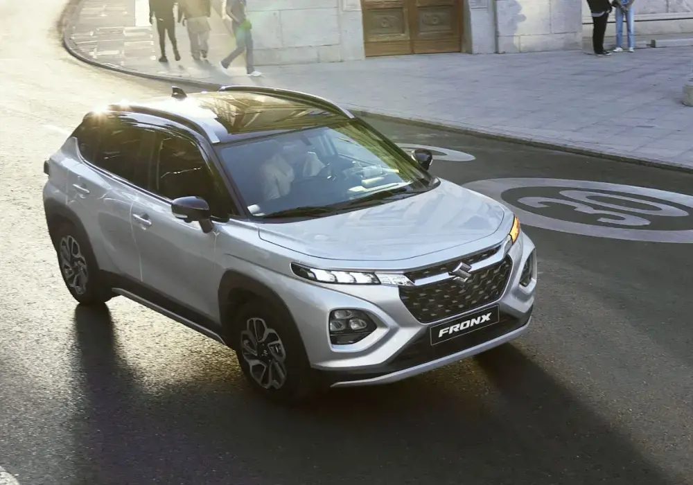Suzuki Fronx plateado estacionado en una calle de la ciudad con una persona al fondo.